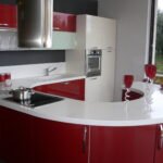 Σύγχρονη κουζίνα με κόκκινα έπιπλα και λευκή επιφάνεια.