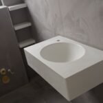 Μοντέρνα λεκάνη σε μπάνιο με γκρίζους τοίχους.